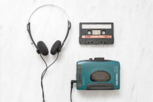 On a white background we can see a walkman, a cassette and wired headphones.