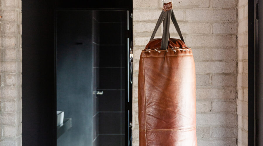 In a room set in rustic, we can see a punching bag, hanging from chains secured to the ceiling.